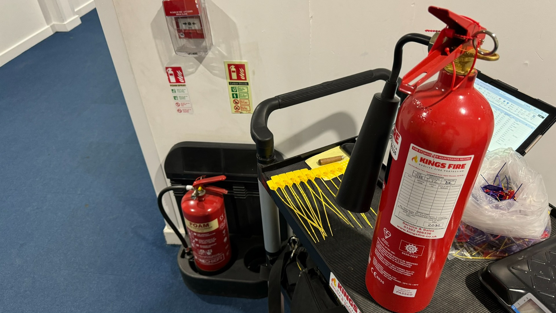 Kings Fire engineer carrying out fire extinguisher servicing in a UK school corridor